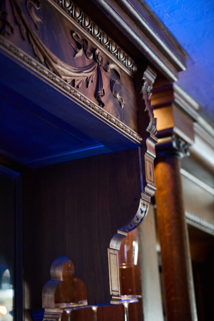 Custom bar design showcasing reclaimed wood carving and architectural details and unique custom lighting by Drury Designs Inc.